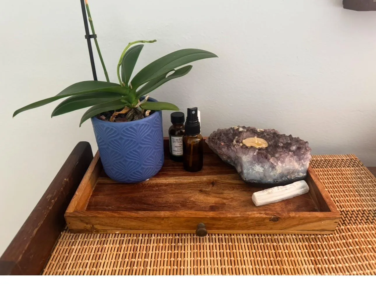 A wooden tray with an orchid, massage oil, and an amethyst crystal